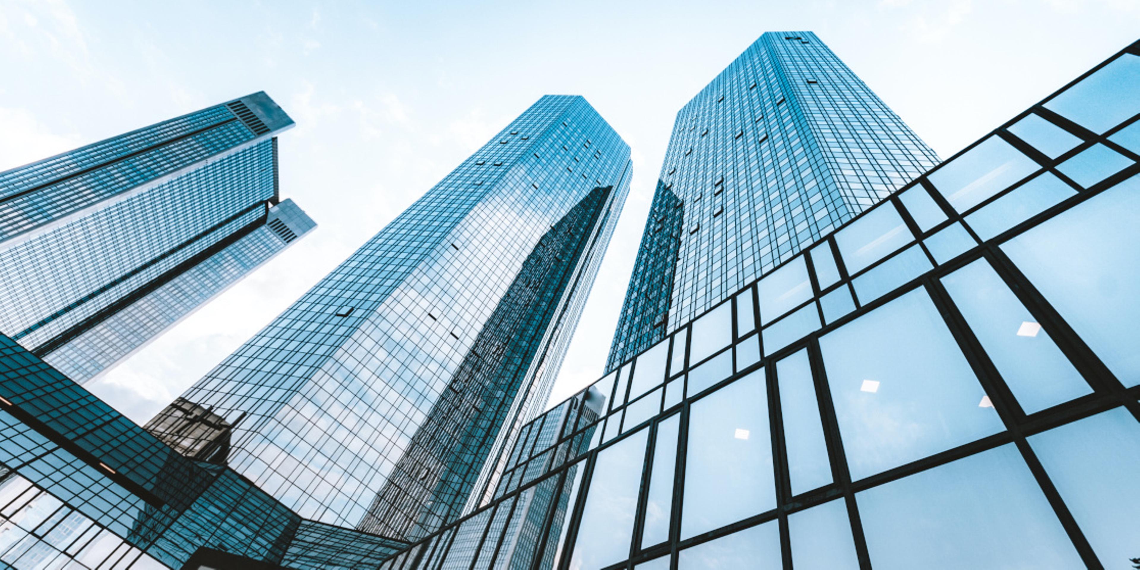 A photo looking upwards at a few skyscrapers.