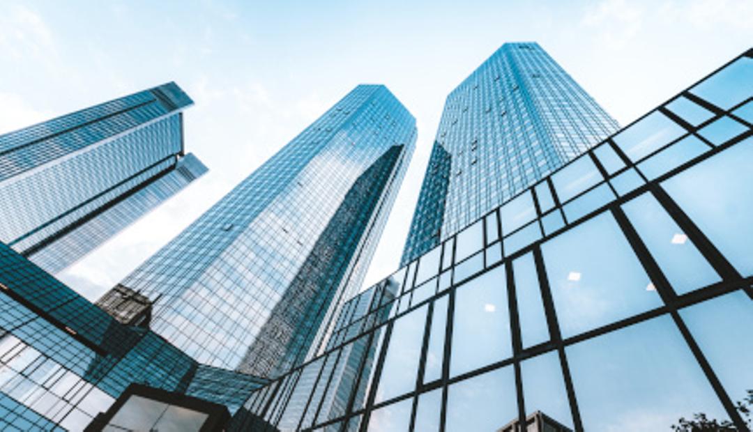 A photo looking upwards at a few skyscrapers.